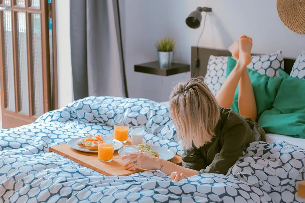 Una ragazza fa colazione sul letto di una stanza d'hotel