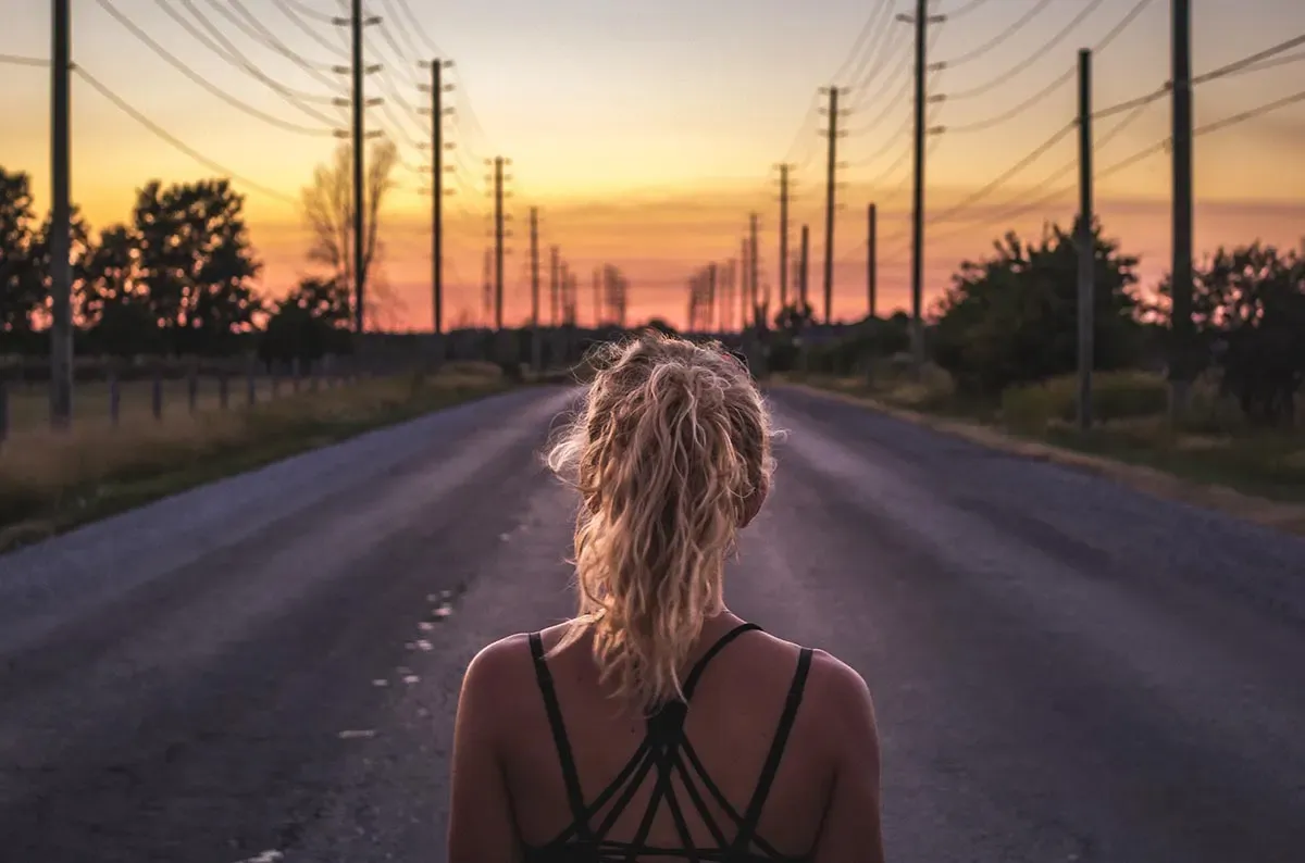 Una runner di spalle su una strada di campagna al tramonto
