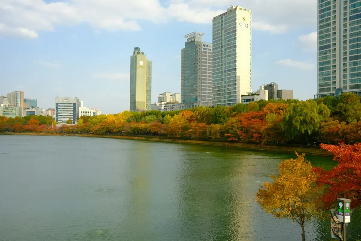 Il lago Seokchon con gli alberi in autunno e i grattacieli sullo sfondo