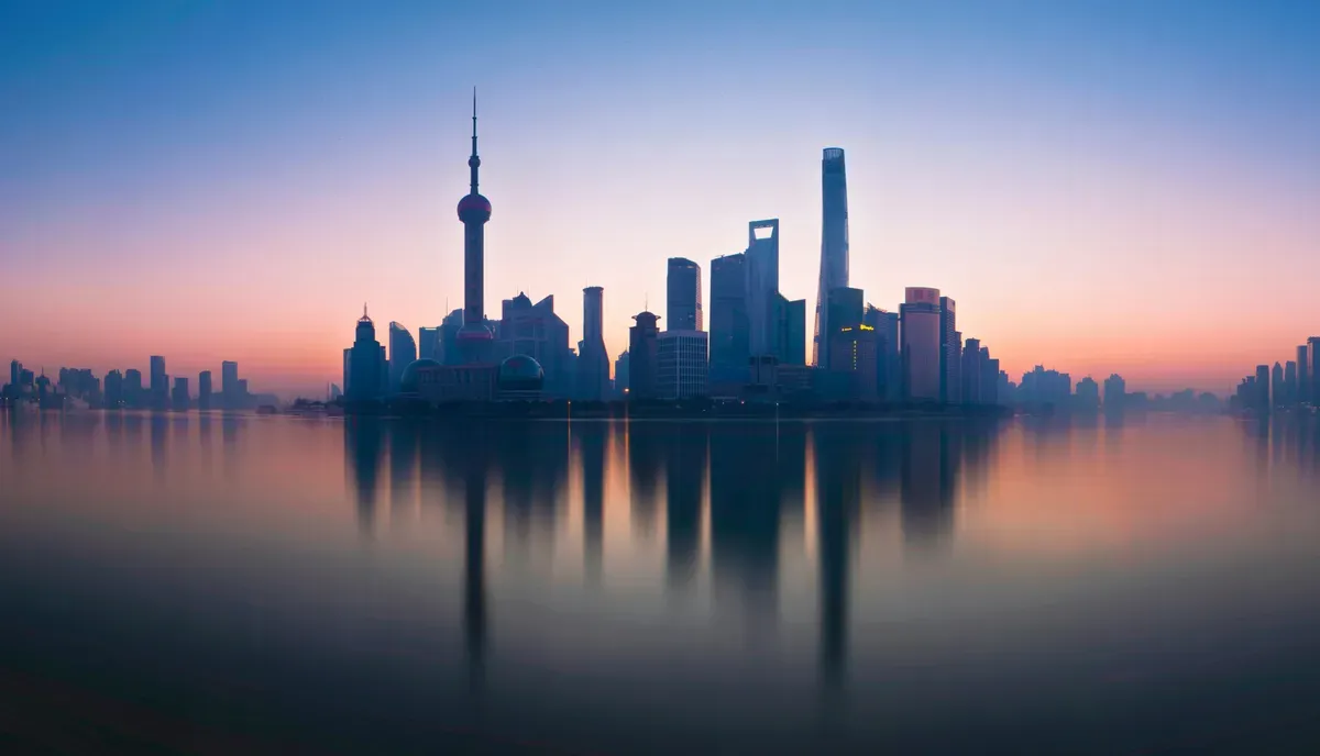 Lo skyline di Lujiazui all'alba riflesso nel fiume Huangpu, a Shanghai