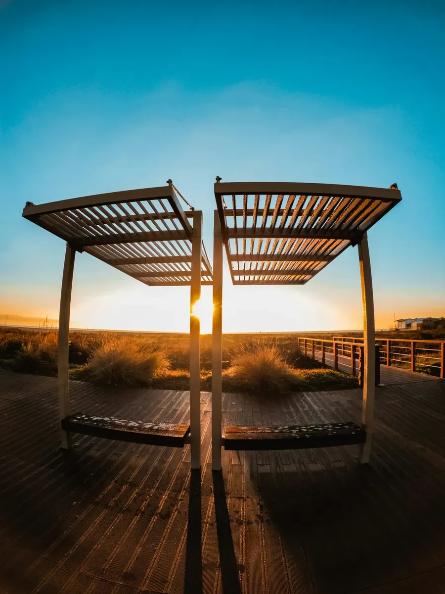 Una passerella in legno con una pergola al tramonto