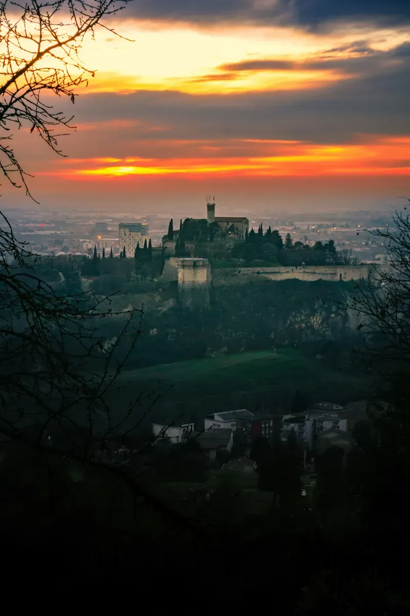 Una collina con un castello e la città ai piedi, all'imbrunire