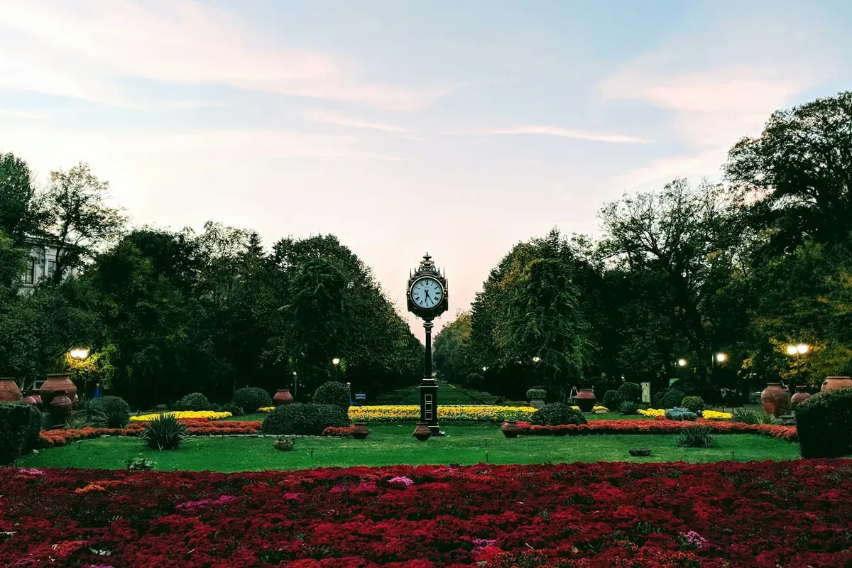 Le aiuole fiorite e l'orologio del Parco Cișmigiu a Bucarest, al tramonto