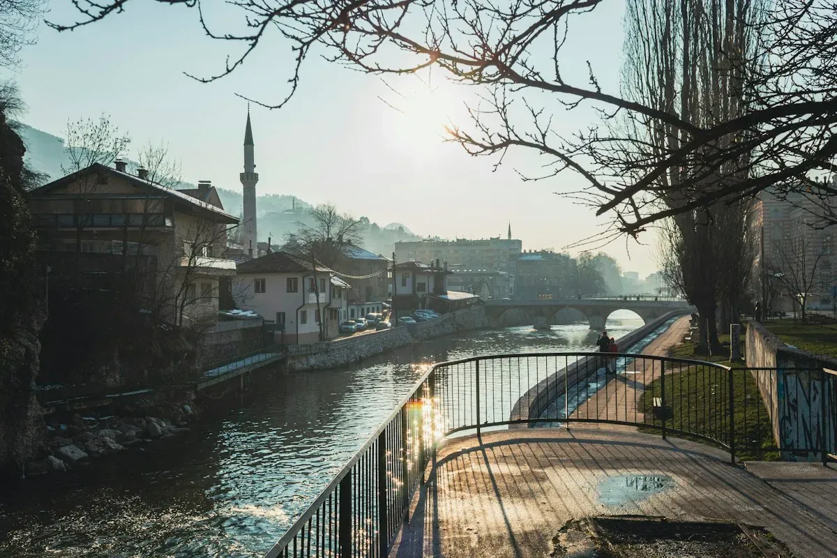 La Miljacka nel centro di Sarajevo, con la passeggiata lungo il fiume, un minareto e un ponte sullo sfondo