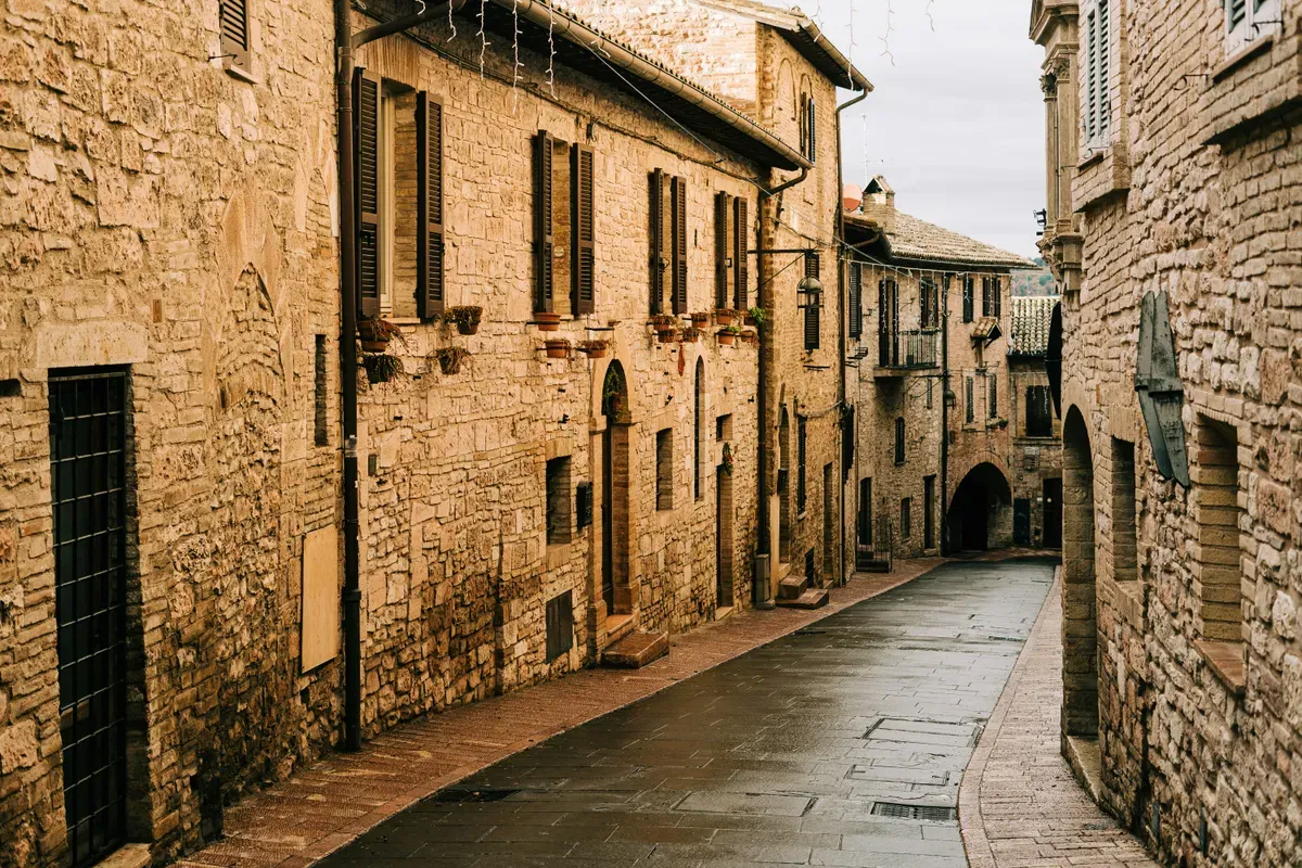 Una via lastricata tra le case in pietra di un centro storico umbro