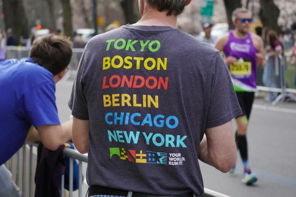 Un runner con la maglietta delle maratone Major tra gli spettatori della Maratona di Boston