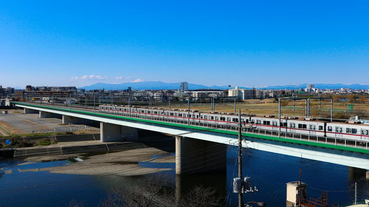 Il fiume Tamagawa con un treno sul ponte e il monte Fuji all’orizzonte