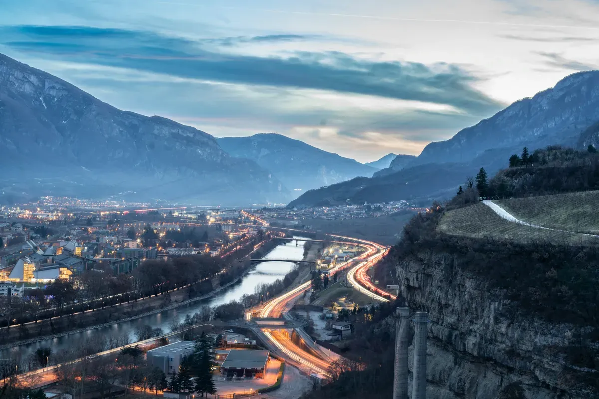La valle dell'Adige a Trento all'imbrunire, con il fiume e le montagne