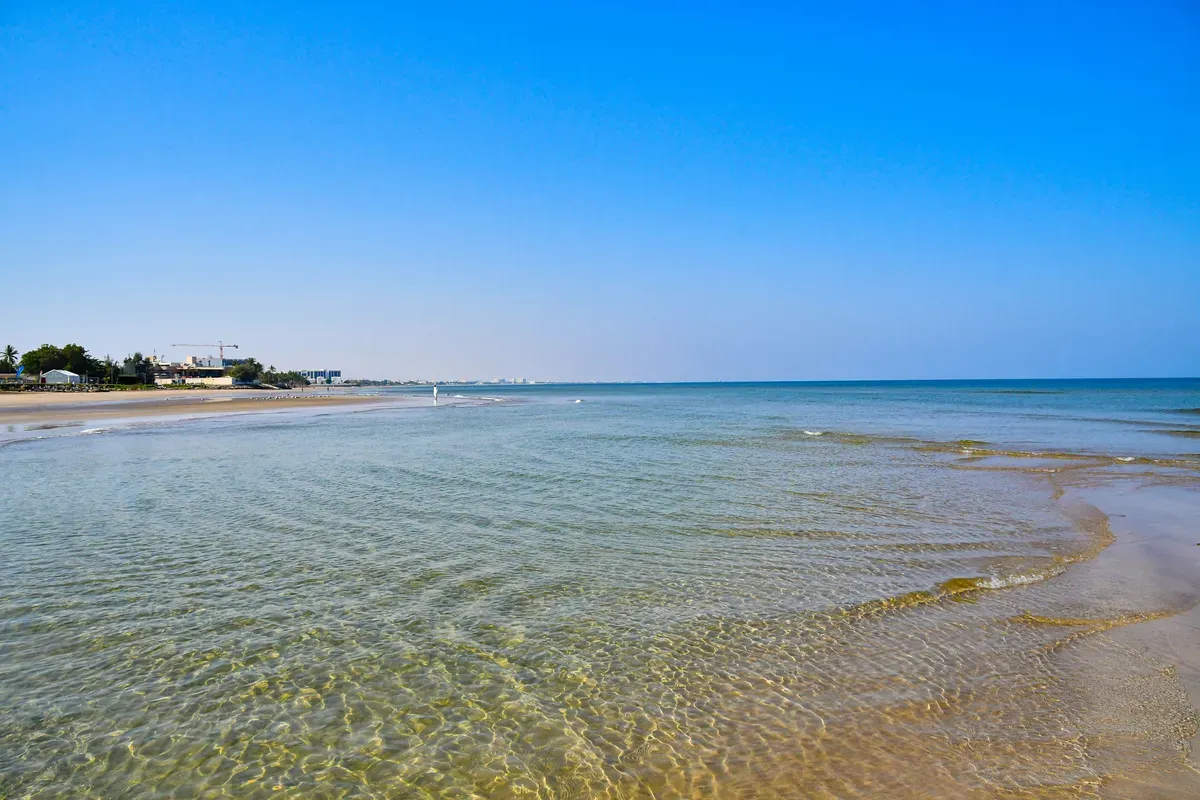 Una spiaggia di sabbia sul golfo di Oman con l'acqua bassa e trasparente