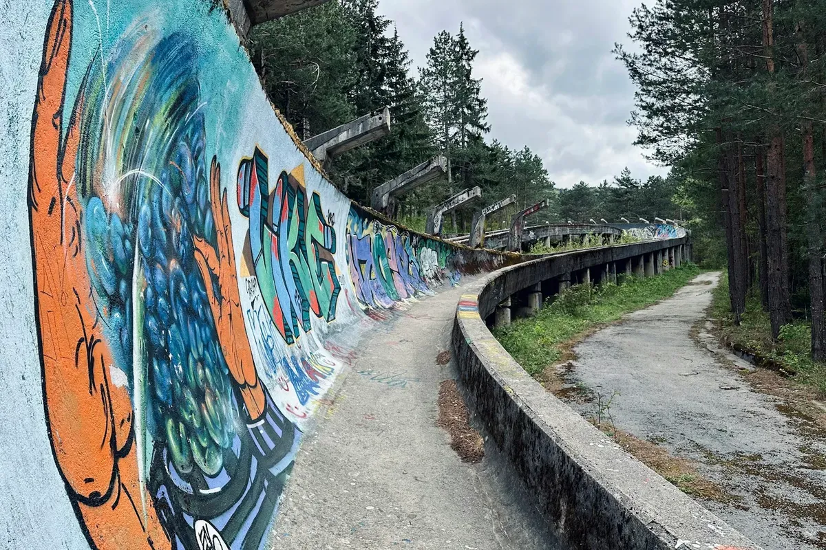 La vecchia pista di bob olimpica del Trebević, coperta di graffiti, con il sentiero che la costeggia nel bosco