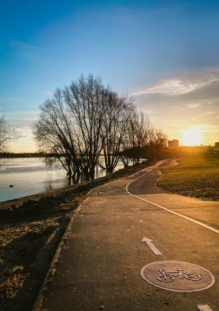 Una pista ciclabile lungo un fiume al tramonto