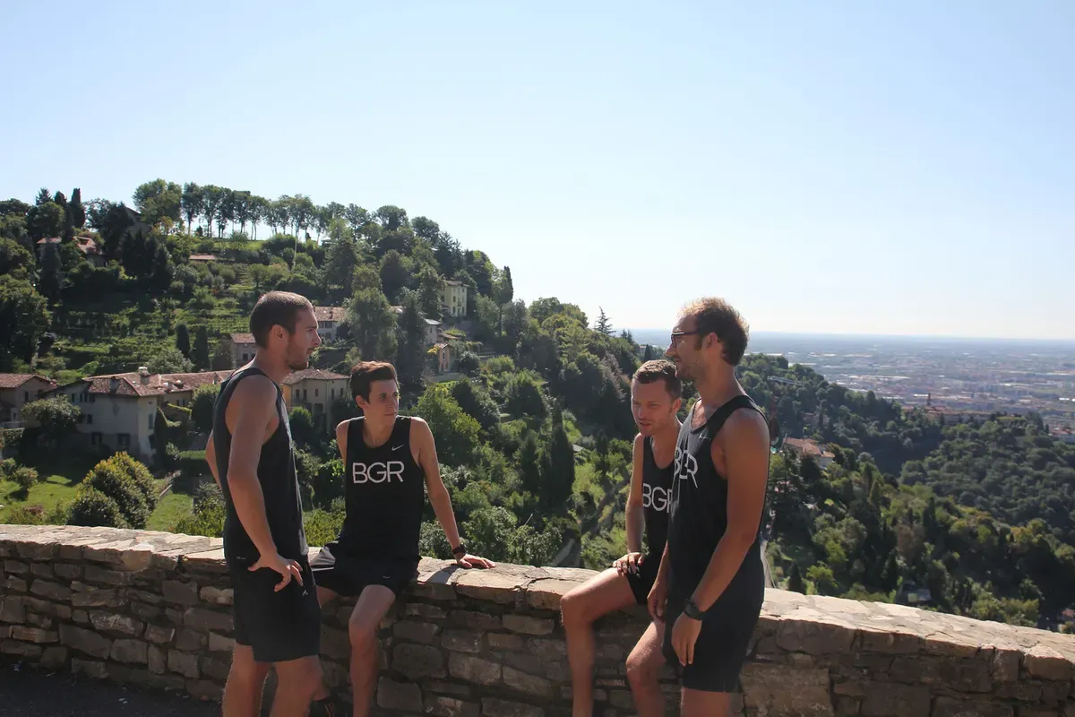 Quattro runner del Bergamo Running sulle mura di Città Alta, con la pianura sullo sfondo