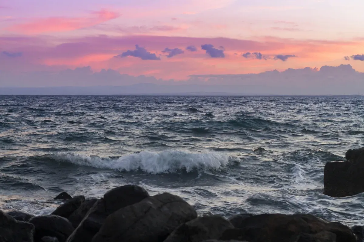 Le onde che si infrangono sugli scogli di lava al tramonto