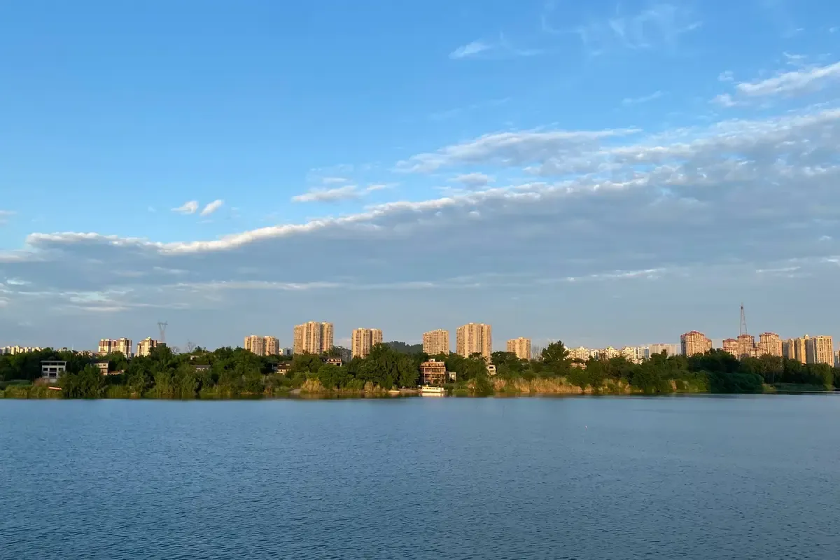 Un lago di Chengdu con la città sullo sfondo, sotto il cielo azzurro
