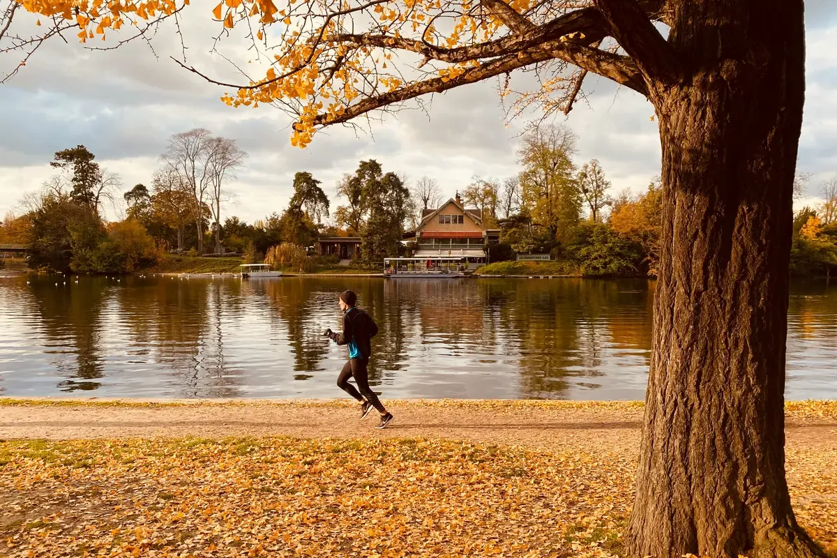 Un runner lungo il Lac Inférieur del Bois de Boulogne in autunno, con il Chalet des Îles sullo sfondo