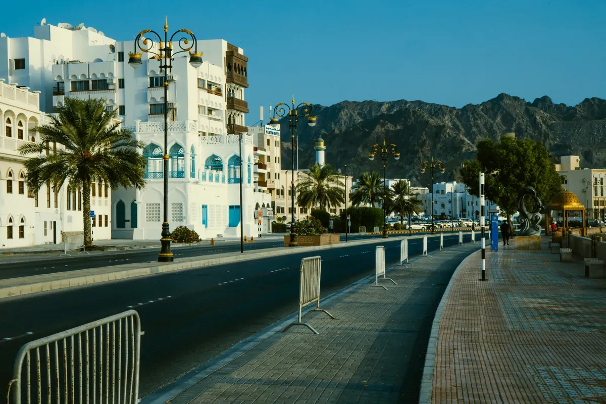 Un ampio marciapiede con le palme lungo una strada di Muscat