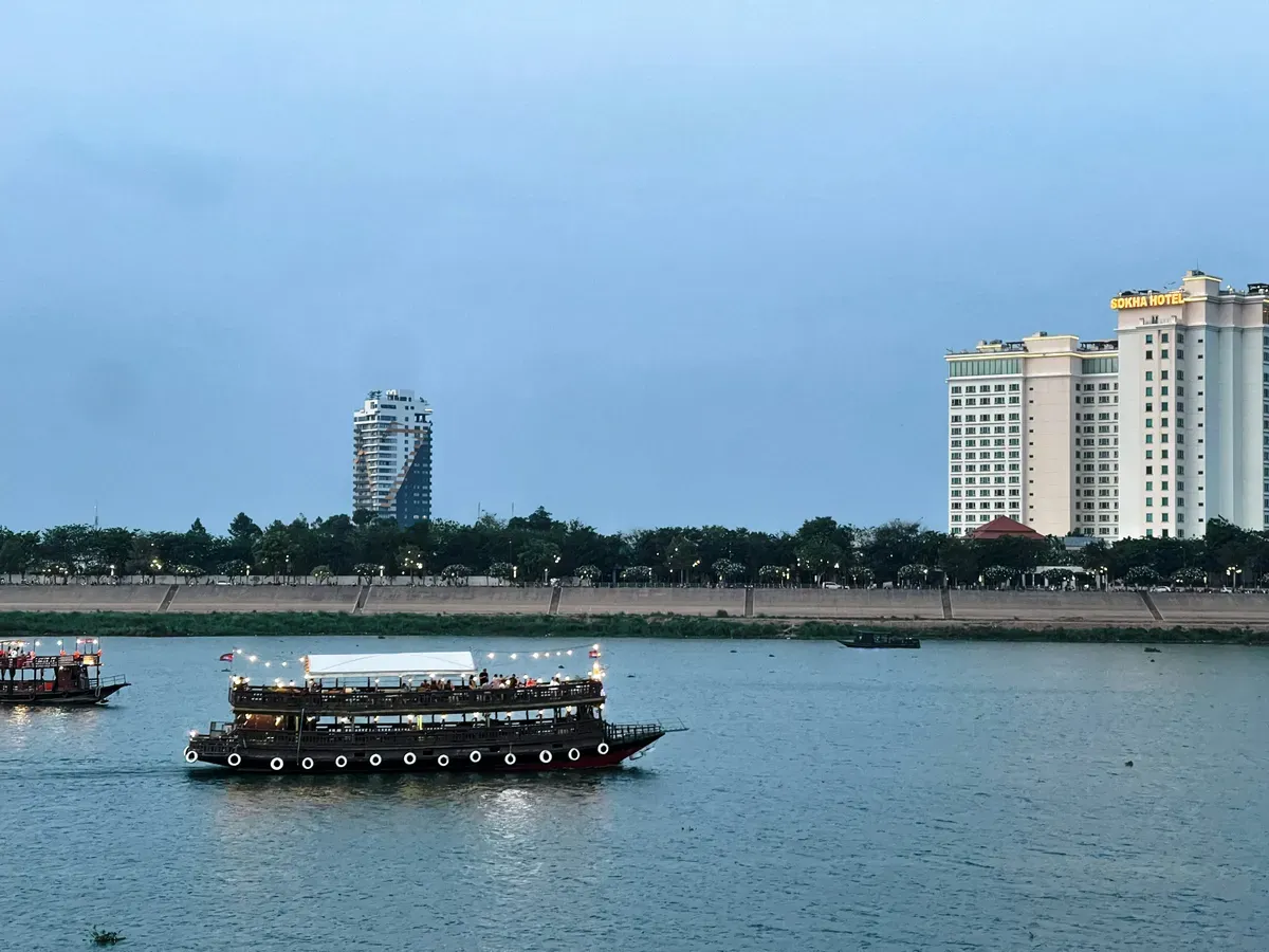 Un battello sul fiume a Phnom Penh, con i palazzi sulla riva