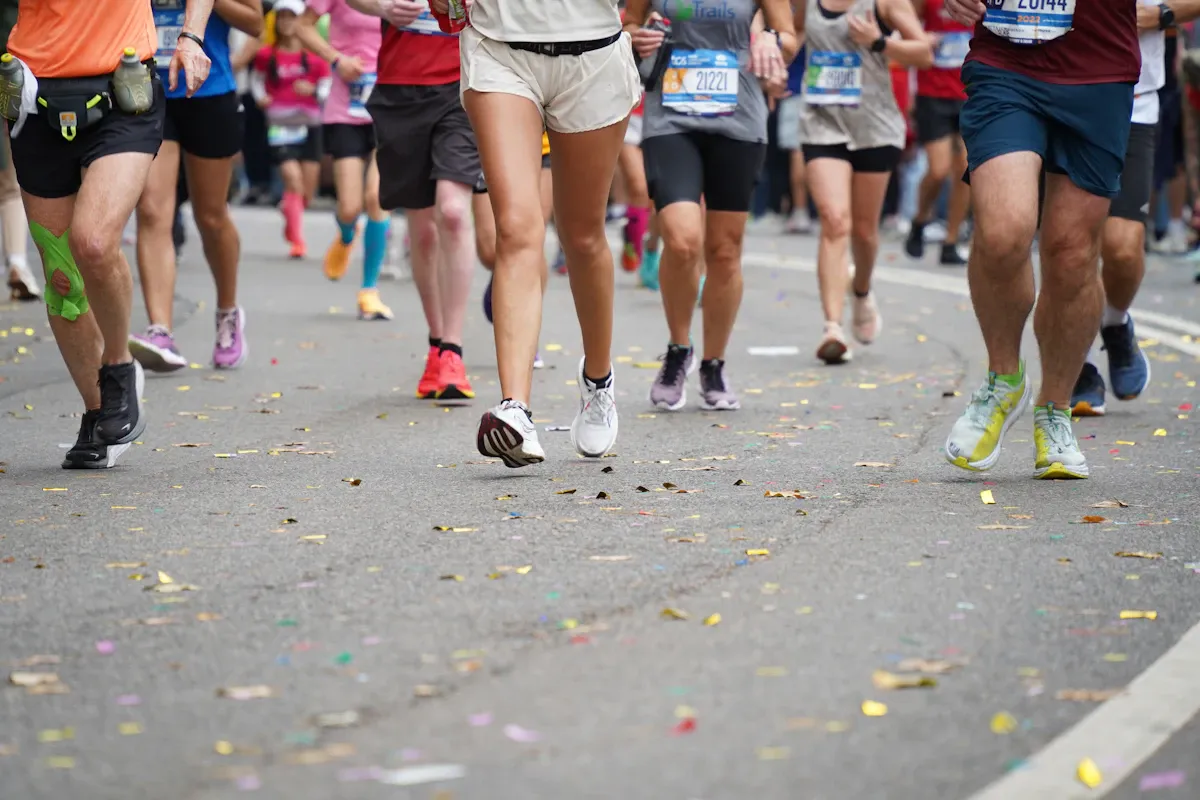 Gambe di runner sull'asfalto di Central Park, cosparso di coriandoli, durante la maratona di New York
