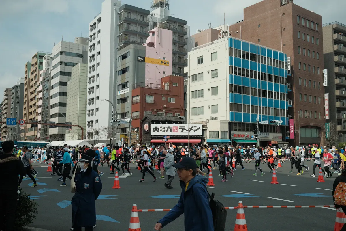 Runner della maratona di Tokyo su una strada transennata tra i palazzi