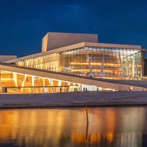 Il Teatro dell'Opera di Oslo illuminato di sera, riflesso nell'acqua