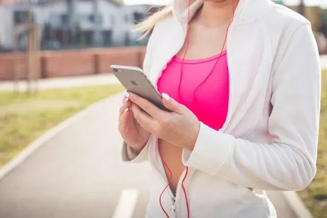Ragazza che guarda lo smartphone, dove non mettere il telefono mentre si corre