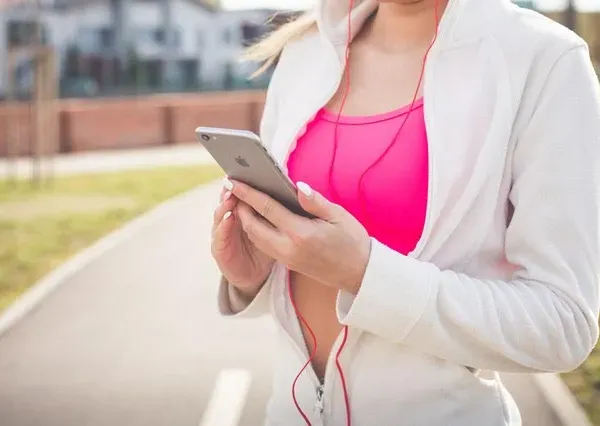 Ragazza che guarda lo smartphone, dove non mettere il telefono mentre si corre