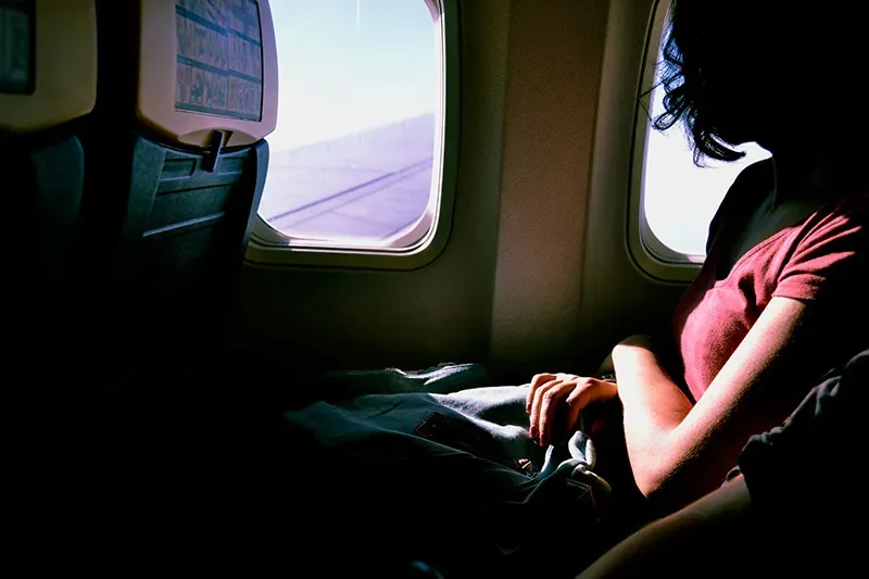Una ragazza seduta accanto al finestrino di un aereo