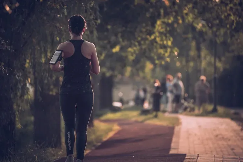 Una runner corre su un viale alberato in un parco