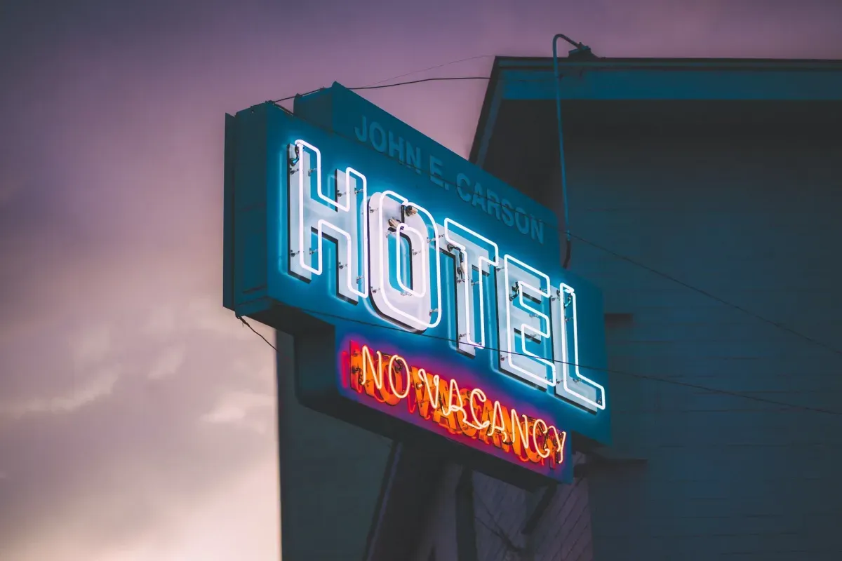 Un'insegna al neon con la scritta Hotel sulla facciata di un edificio al tramonto